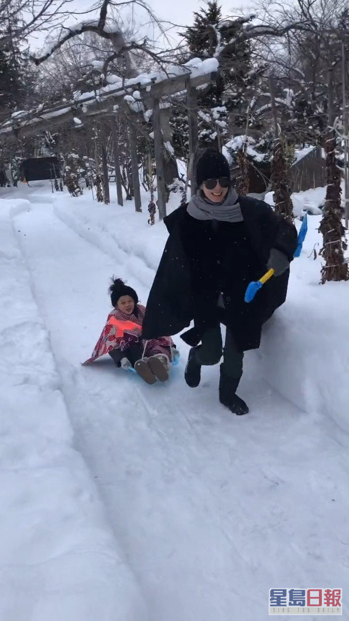 蘇岩在雪地上拉住女兒玩人肉雪橇。