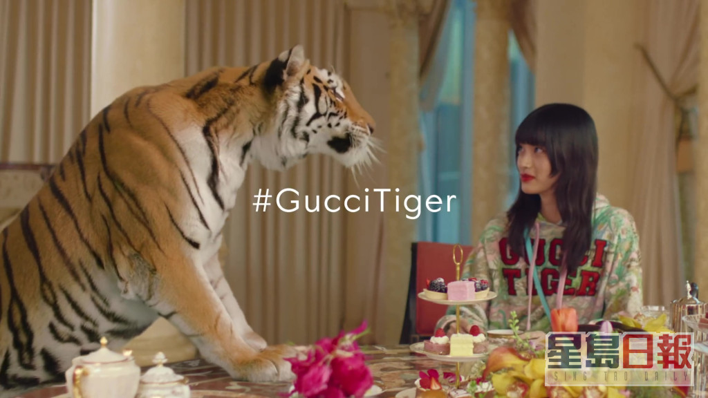 最后一幕为老虎前腿站在众模特儿的圆形餐桌中。Gucci广告截图