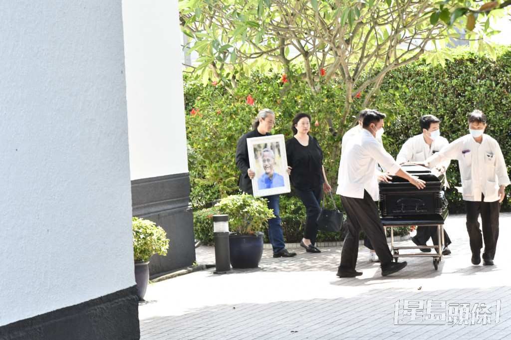 吳嘉龍捧着亡父吳耀漢的遺照，隨靈柩步出教堂。