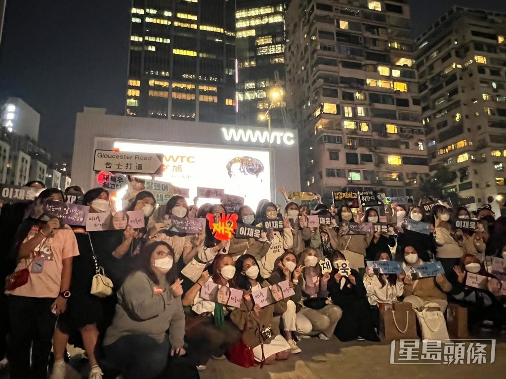 大批粉丝聚集告士打道，背着场外播放李宰旭照片的大屏幕打卡朝圣。