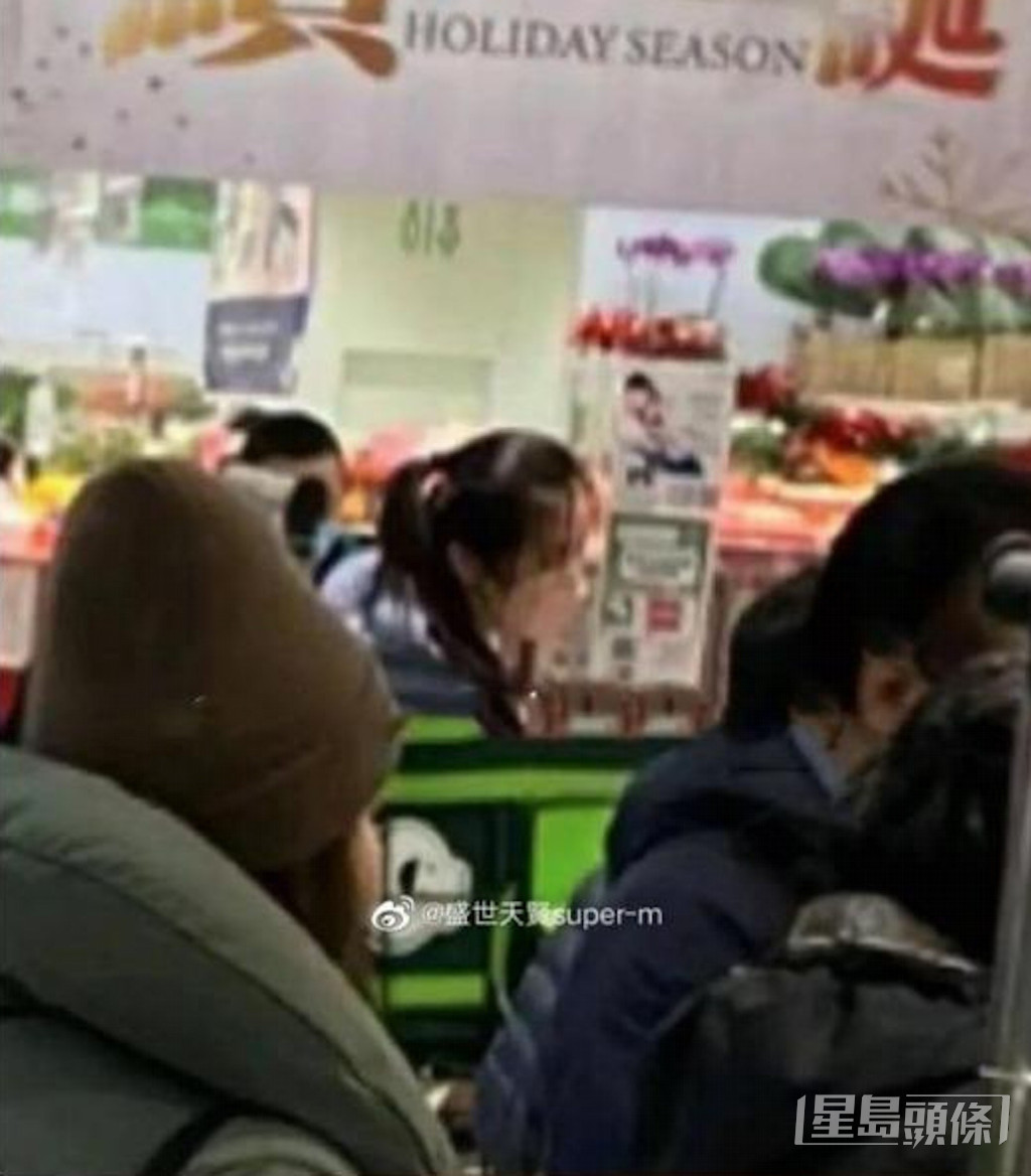 王祖賢身穿藍色的羽絨外套，在超市的人群中排隊等結帳。