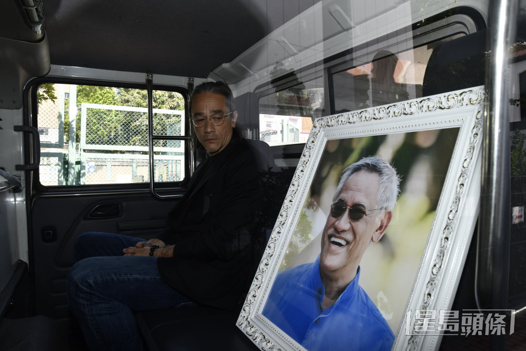 吳嘉龍在車內凝望亡父的遺照時，眼泛淚光。