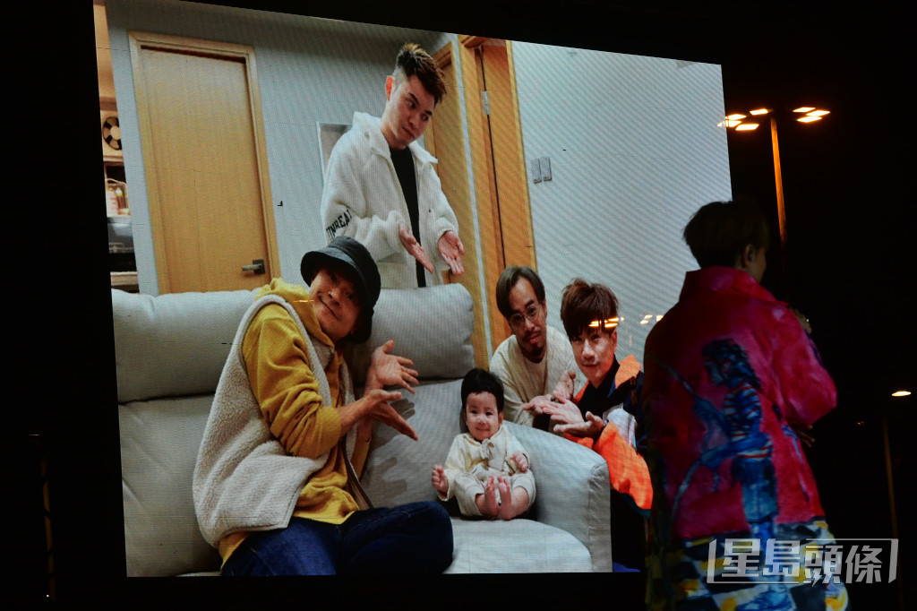 銀幕上播放出四子圍着一個嬰兒的照片。