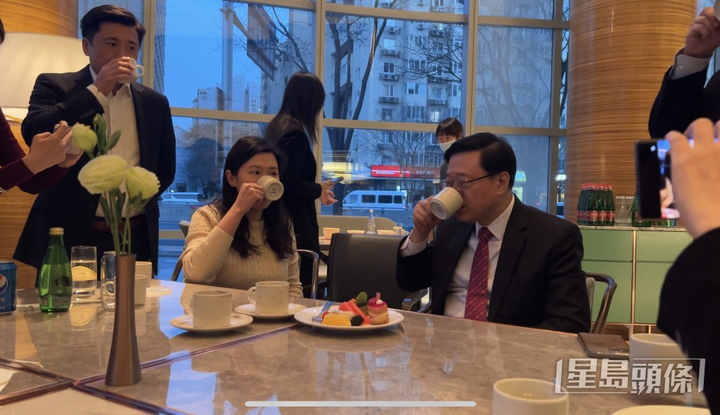 李家超（右1）与一众记者尝试北京传统饮品豆汁，特首办传讯秘书谢振中（左1）亦有出席。