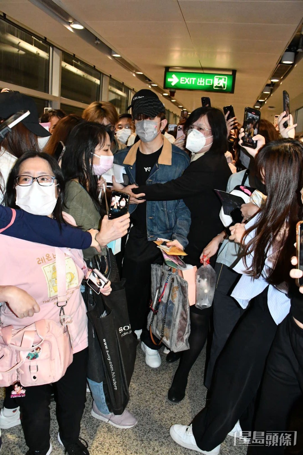 機場女職員無奈地雙手環抱「教主」前進。