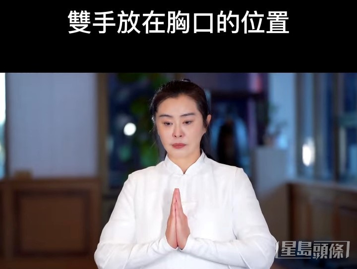 穿上全白中式長袍的王祖賢綁起高馬尾，一臉嚴肅地示範合十及跪拜等動作。