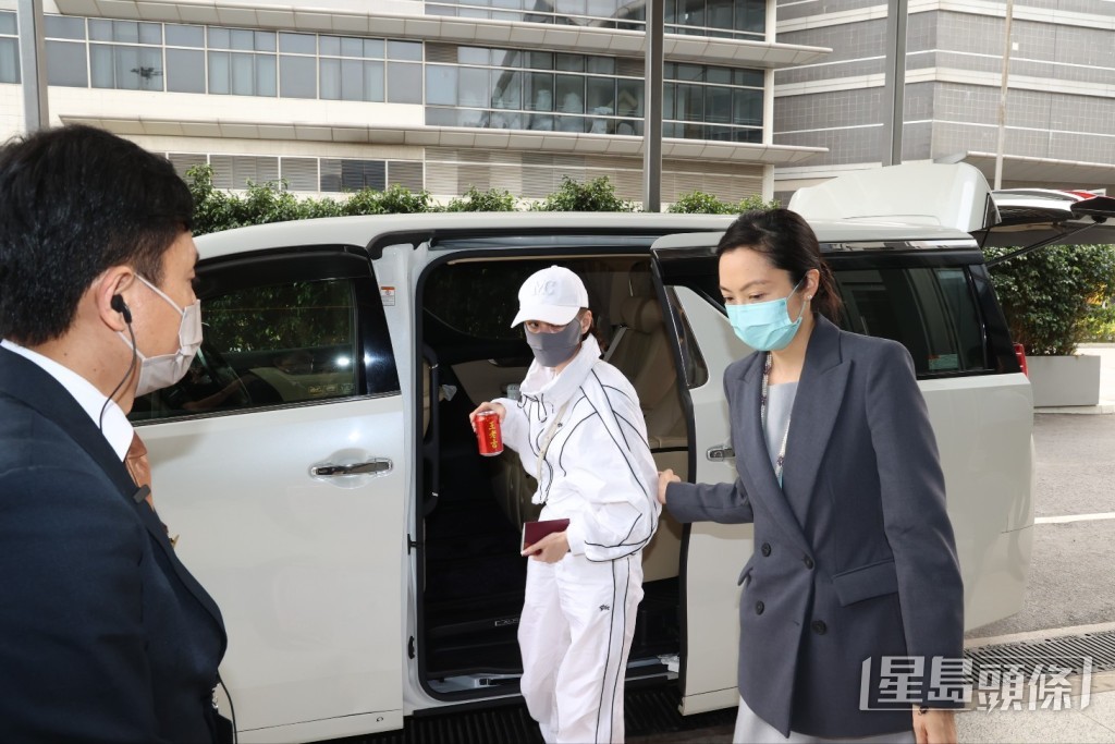 何超蓮以全白運動Look示人，手上還拿着一罐飲品、護照及電話。