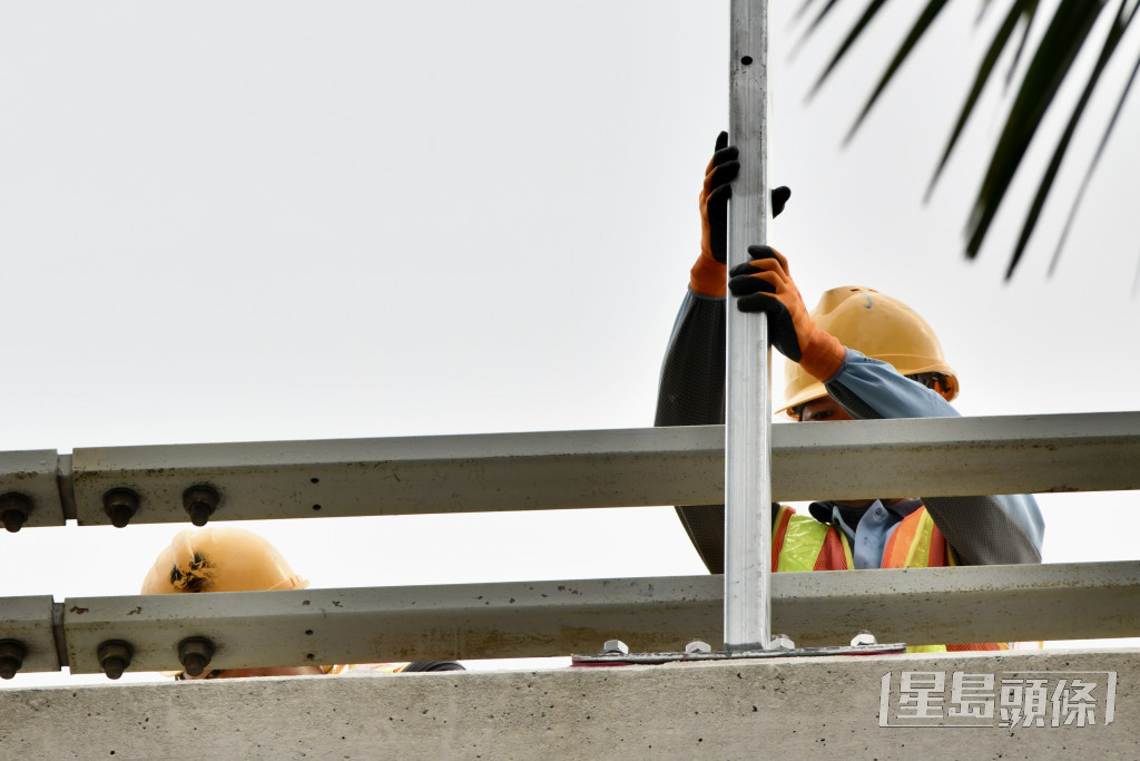 西九龍法院外行車天橋欄杆處，有工人正加裝防護網。盧江球攝
