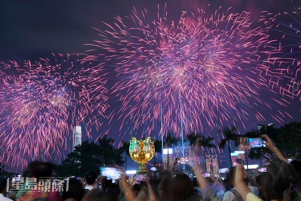 市民举起手机拍摄烟花绽放一刻。苏正谦摄