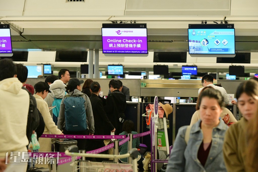 大批旅客排隊等候辦理登機手續。歐樂年攝