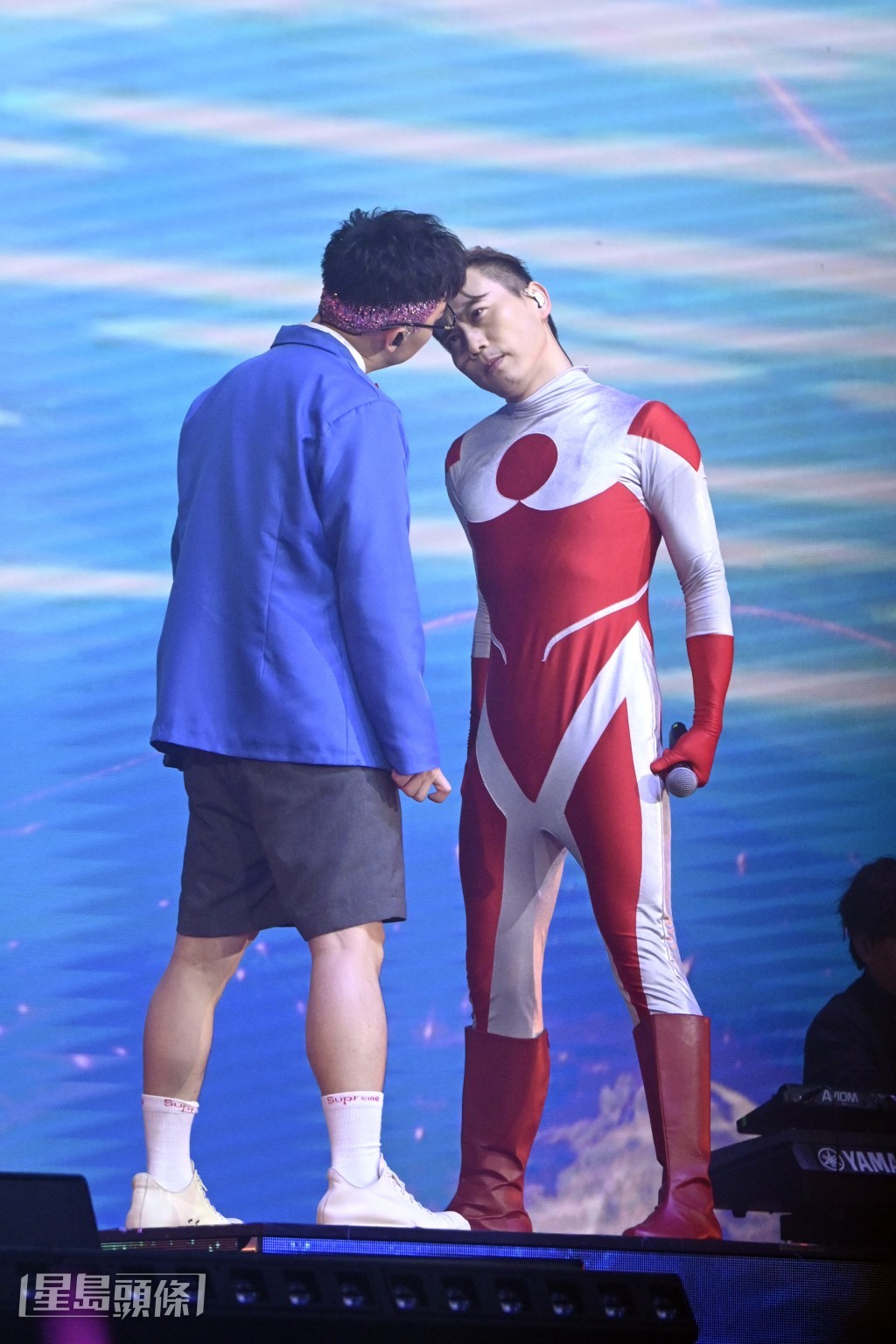 米羔穿上超人緊身衣，與化身「柯南」的輝智唱《超人的主題曲》。