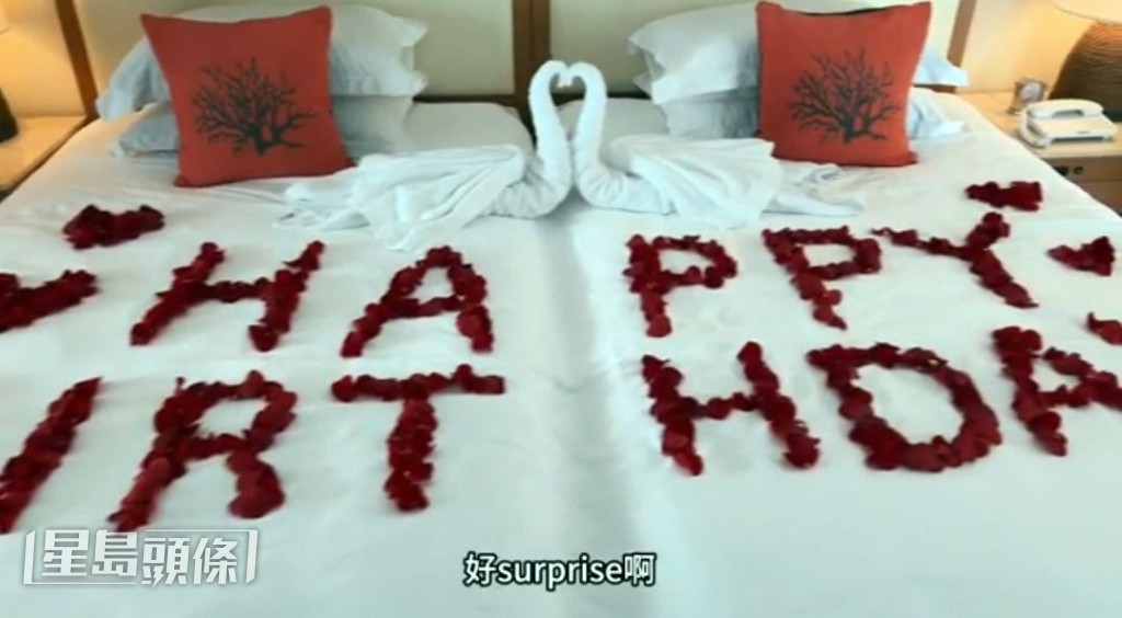 紅玫瑰花瓣佈置嘅雙人床。