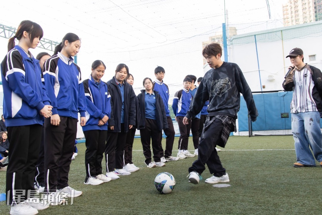 他與99位學生在草地球場上,合共100人挑戰來回傳接足球。 他與99位學生在草地球場上,合共100人挑戰來回傳接足球。