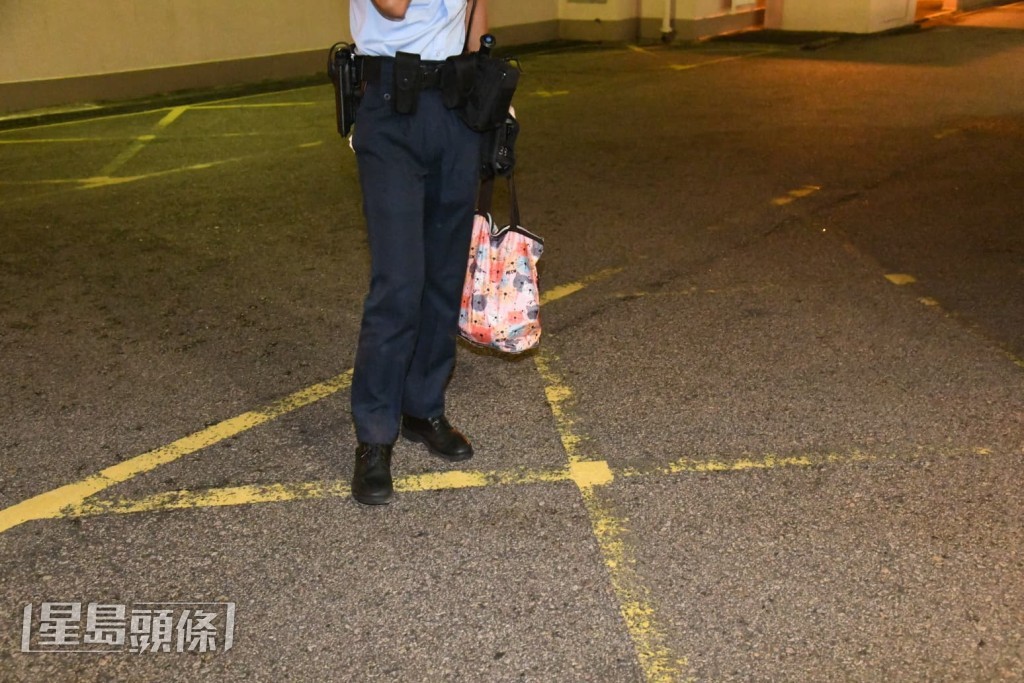 警員在事發現場手持一個相信屬於女事主的手袋。黎志偉攝