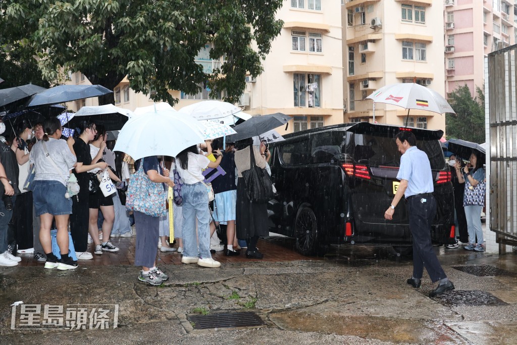 天氣下着滂沱大雨，粉絲撐起雨傘堅守門外。