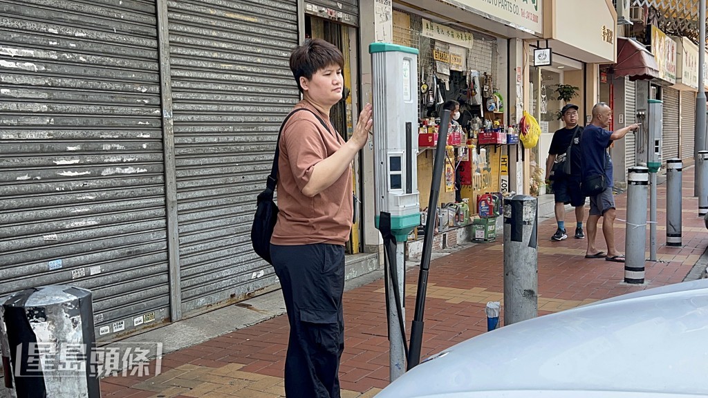 車房老闆娘替店前車輛入錶。楊偉亨攝 車房老闆娘替店前車輛入錶。楊偉亨攝