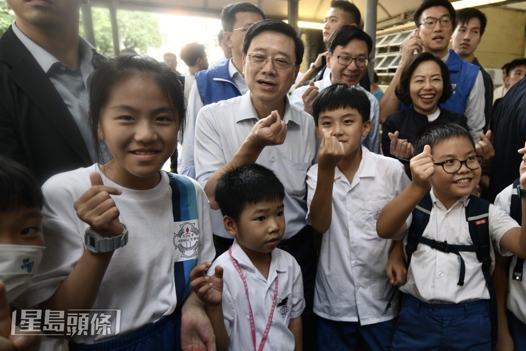 李家超早前落區，與多名小學生合照。資料圖片