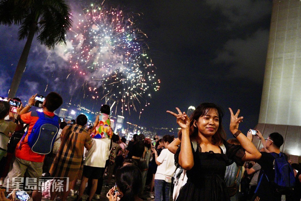 游客对着绽放的烟花拍照。欧乐年摄