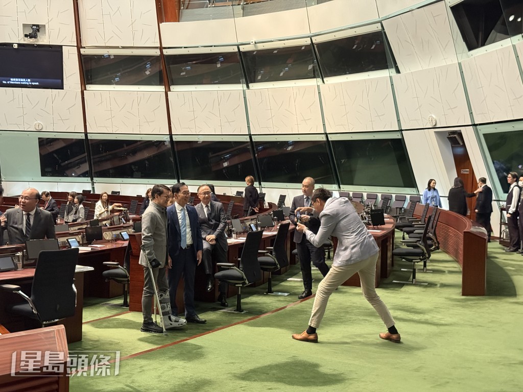 身型高大的工聯會陸頌雄，「扎馬步」俯身為民建聯主席陳克勤、保險界陳健波拍照。曹露尹攝