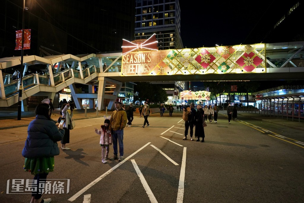 市民走出马路与圣诞灯饰合照。