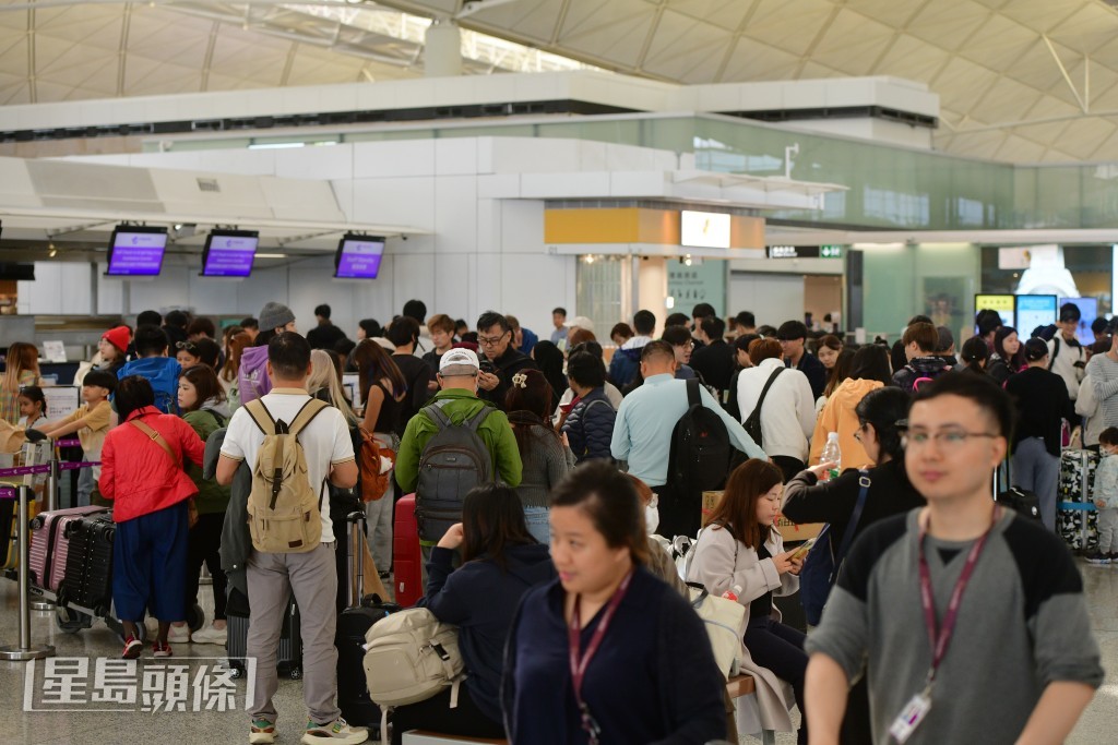 大批旅客排隊等候辦理登機手續。歐樂年攝