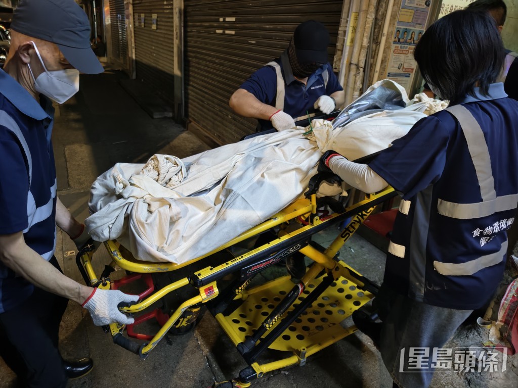 仵工將男死者的遺體搬落樓。