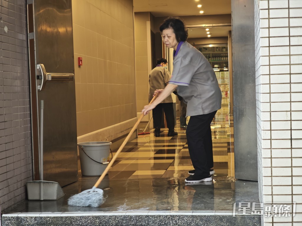 清潔工人試圖將積水推出商場外。 