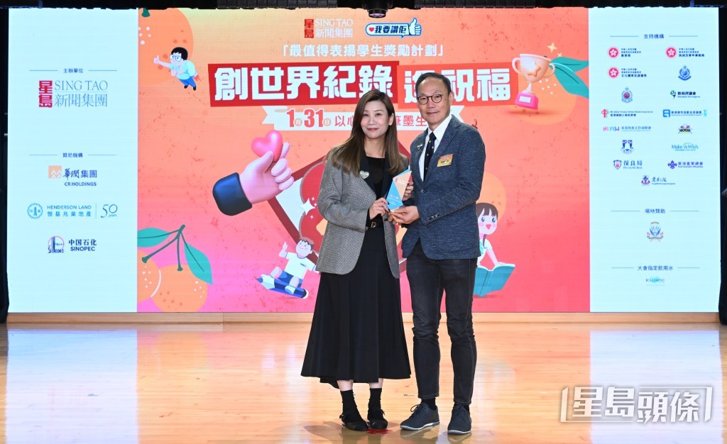《我要赞佢》项目总监陈韵文（左）向香港童军总会香港总监（管理）卢建业致送感谢状。