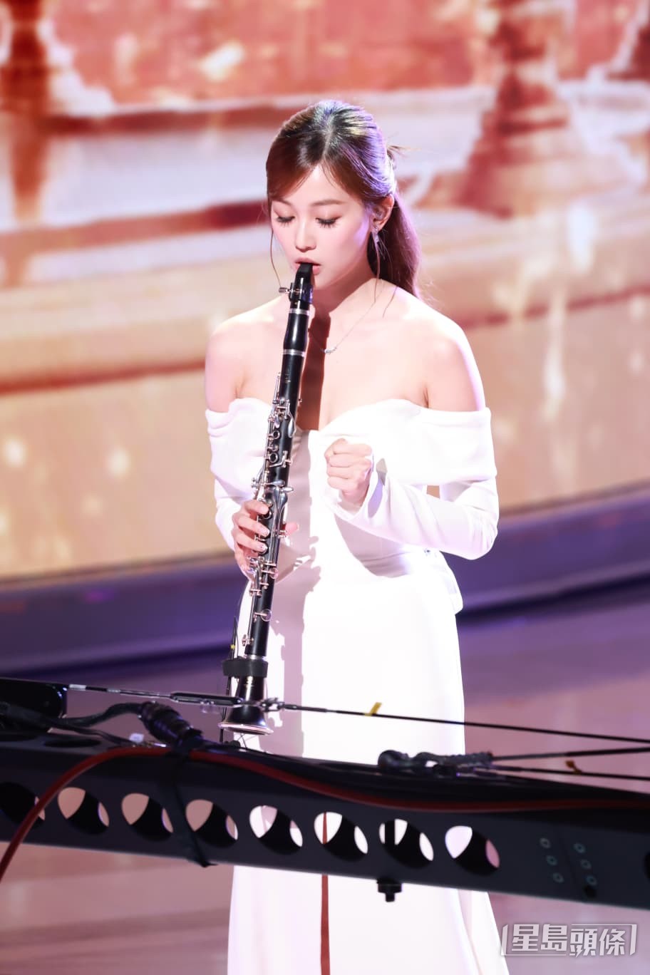 郭柏妍身穿白色露肩晚裝仙氣登場，專注吹奏單簧管。