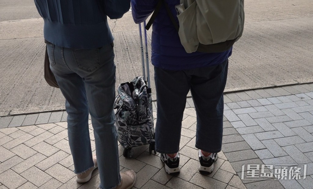 黃女士手拉着購物車，並孭着背囊。