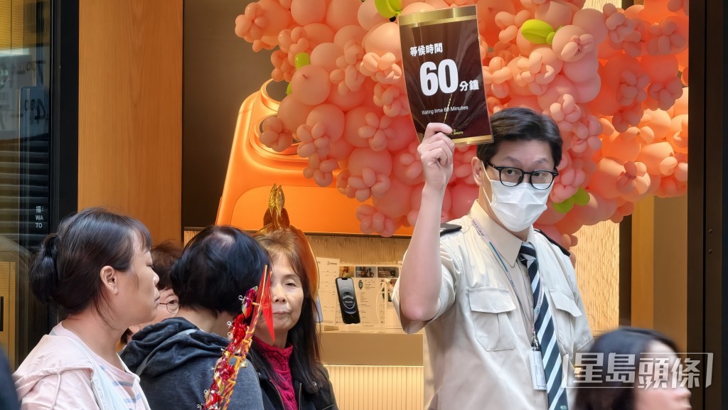 馬會職員舉牌,提醒市民預計輪候時間。 馬會職員舉牌,提醒市民預計輪候時間。