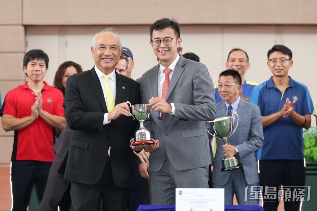 香港賽馬會兩地馬房營運部主管鄭奇龍（左）將「最安全及整潔馬房獎」的馬房獎項頒予徐雨石馬房的助理練馬師戴兆麟（右）。