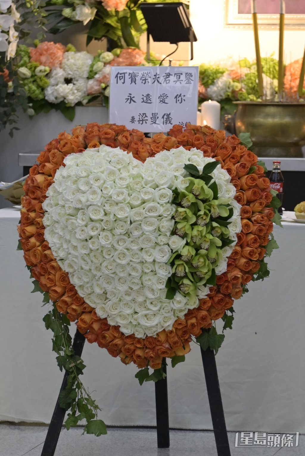 遺孀何梁曼儀的心形花牌放在何寶榮遺照前方。 遺孀何梁曼儀的心形花牌放在何寶榮遺照前方。