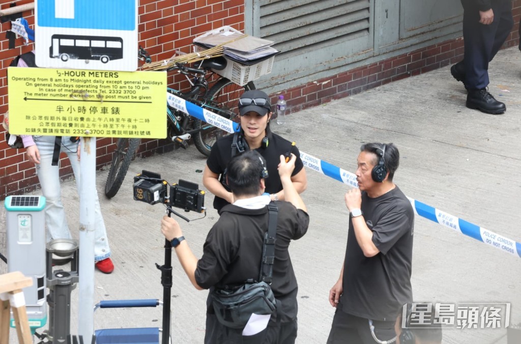周殷廷在警方封鎖線旁與攝影團隊深入商討鏡頭角度，確保畫面呈現最佳張力。