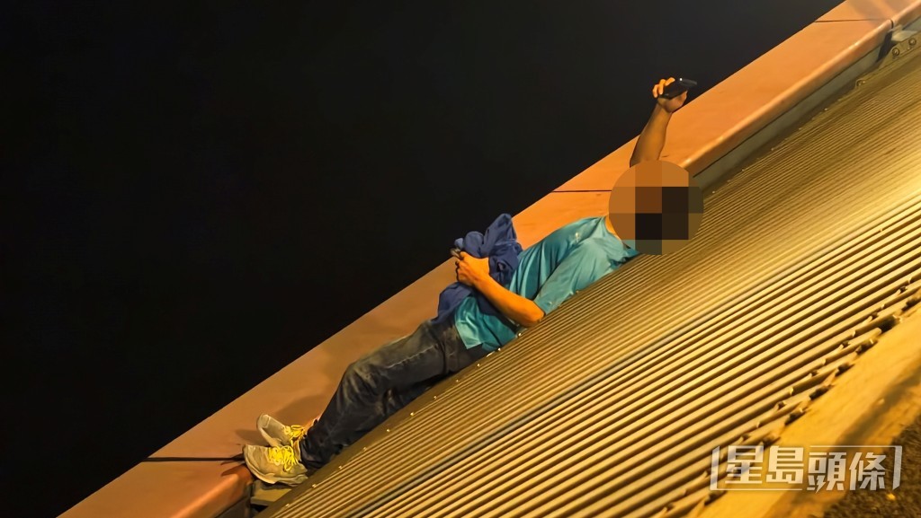 男子不時舉手機拍攝橋面的救援人員及傳媒。