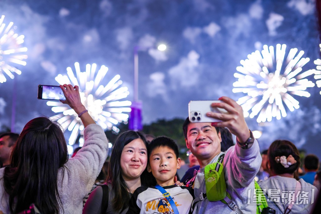 不少人舉起手機捕捉煙花的精彩畫面,亦有人與煙花合照「打卡」。 不少人舉起手機捕捉煙花的精彩畫面,亦有人與煙花合照「打卡」。