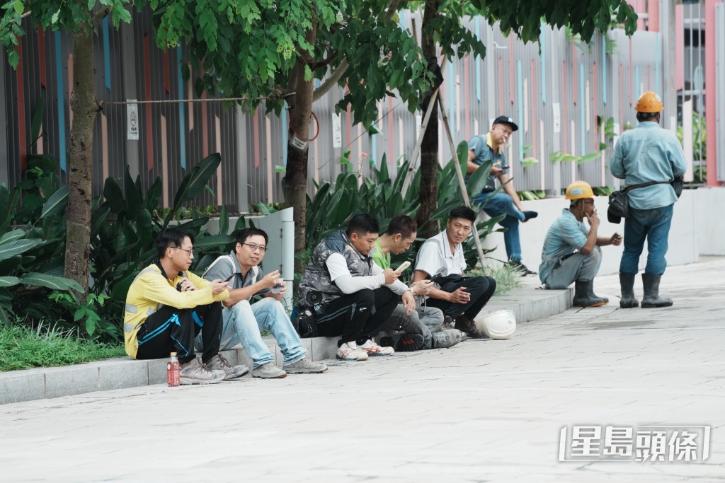 大批工友趁下午茶時段到地盤外的路旁吸煙和休息。