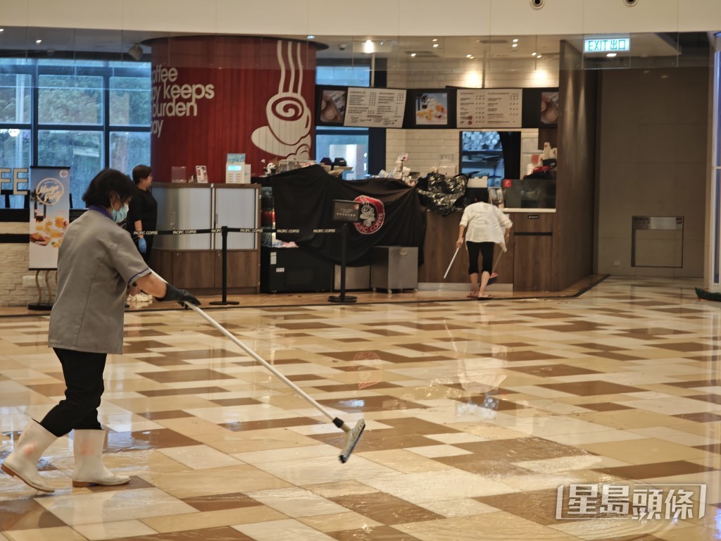 清潔工人試圖清理積水。 