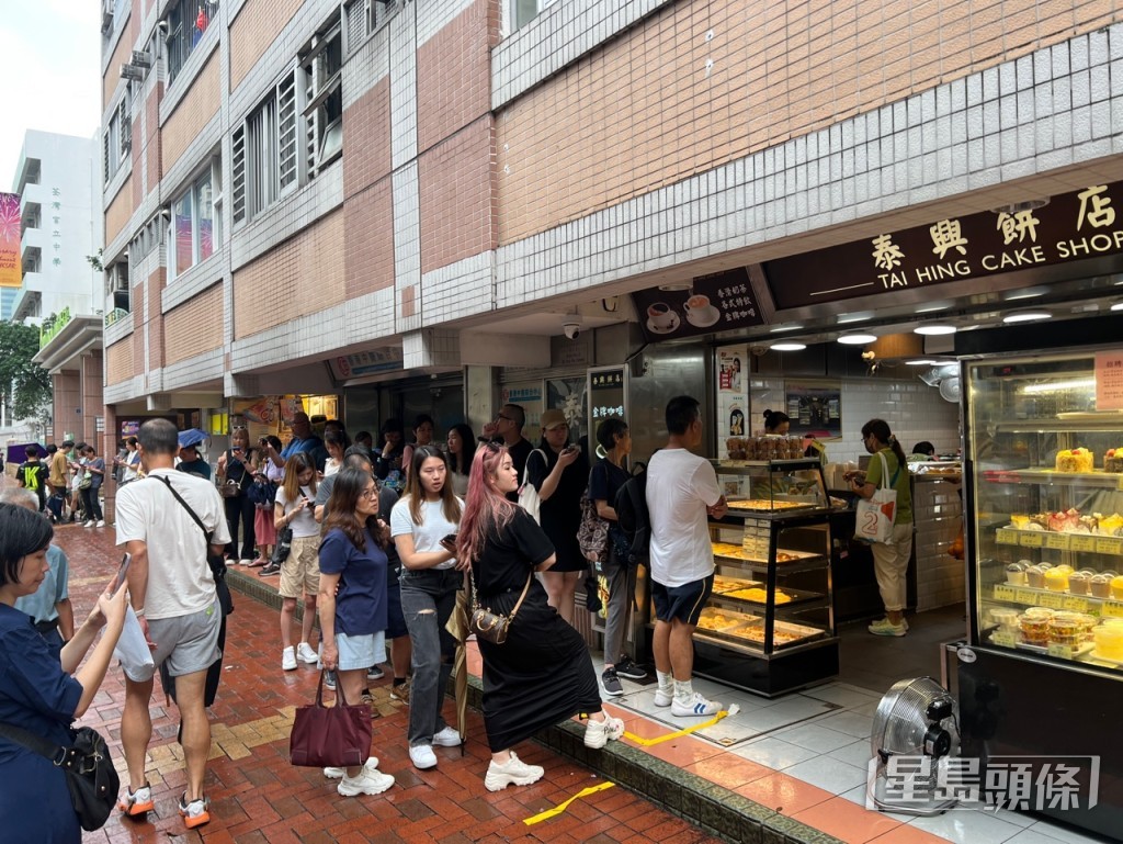 今日间中下起滂沱大雨，下午2时仍有近百人排队购买“热香饼汉堡”。林晓敏摄