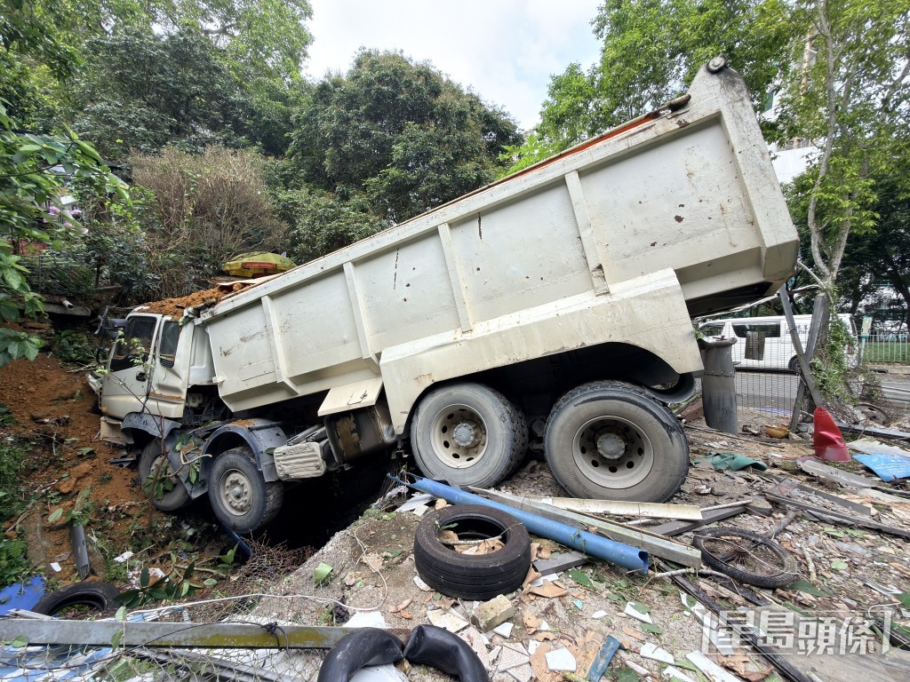 泥頭車被卡在山坡與污水渠間。 泥頭車被卡在山坡與污水渠間。