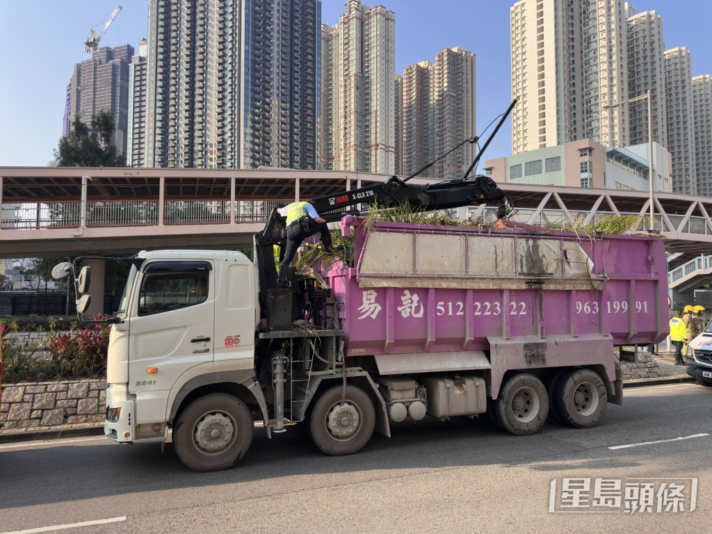 有交通警爬上吊車車斗上，協助將吊臂與架空電纜分開。梁國峰攝