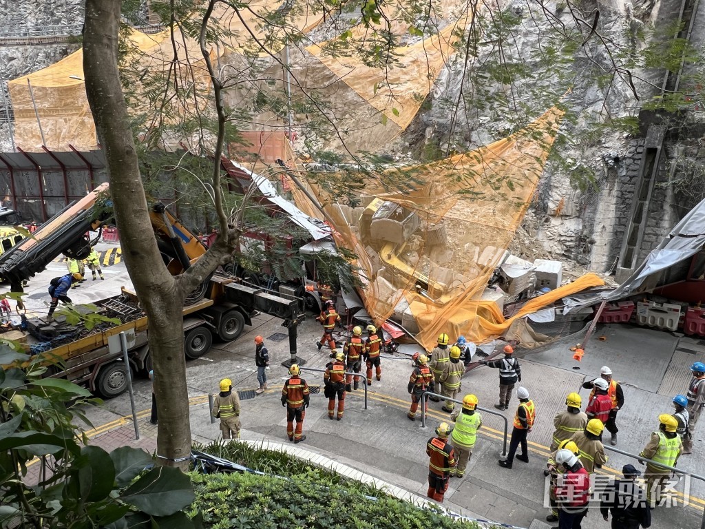 垃圾車被倒塌圍板壓住車頭。