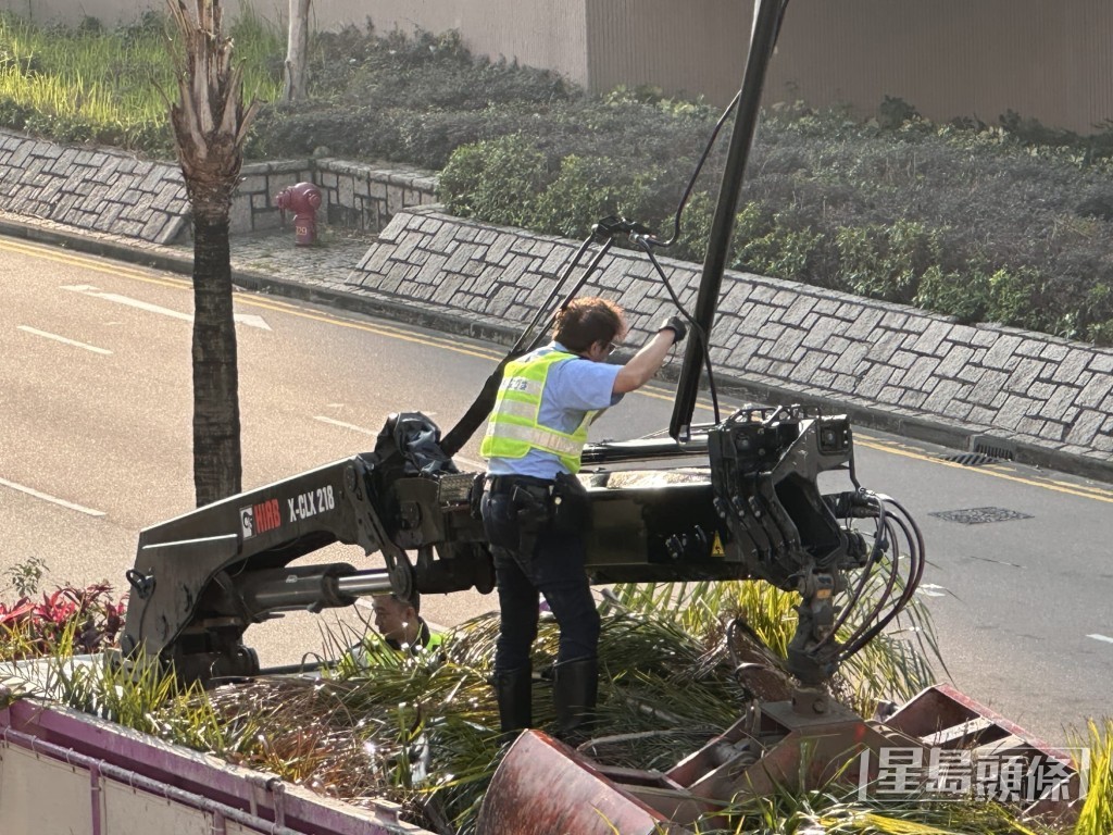 交通警爬上吊車車斗上，協助將吊臂與架空電纜分開。