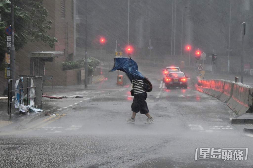 市民撐傘返工，但雨傘亦被吹翻。伍明輝 攝