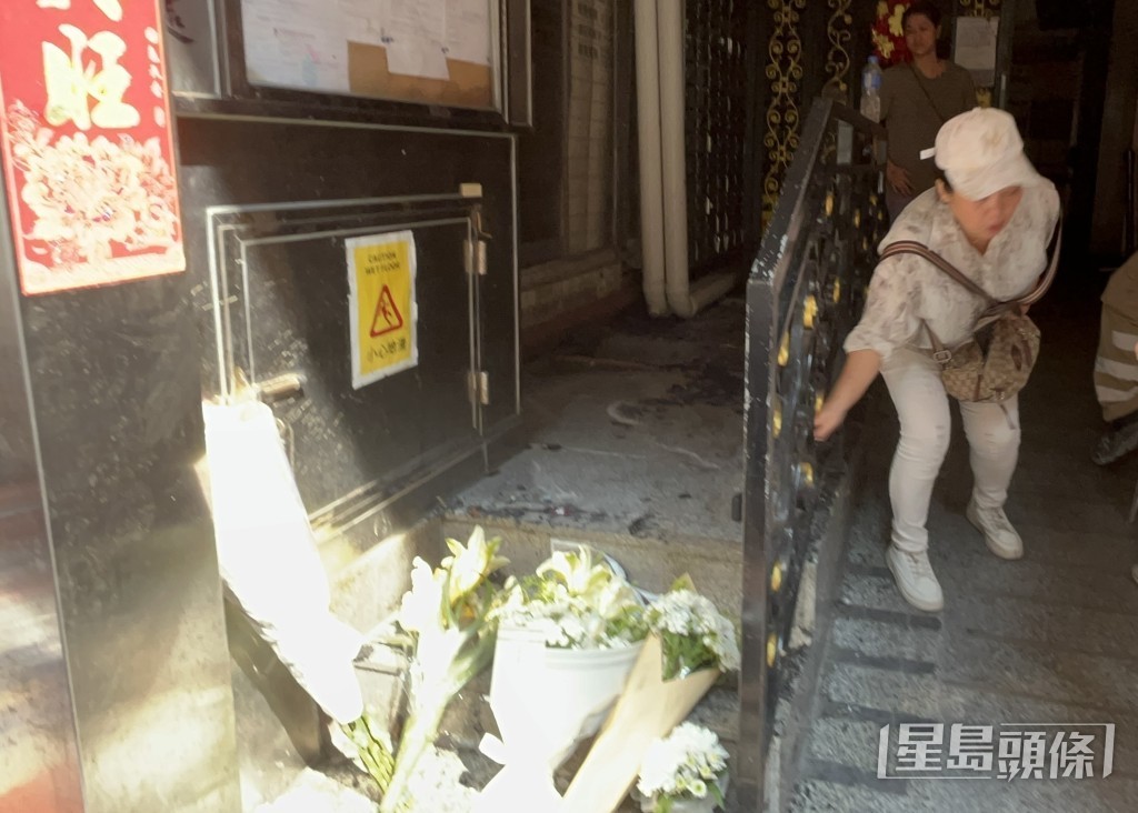 今早仍有街坊在大廈門口擺放鮮花悼念死難者。林思明攝