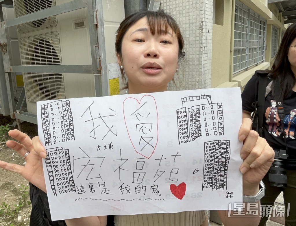 范女士带着儿子有关宏福苑的画作上楼。杨伟亨摄