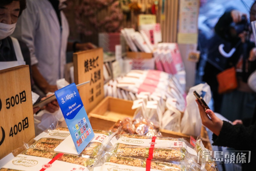 有遊客用電子錢包購買當地傳統小吃、號稱淺草「三大名物」之一的人形燒。