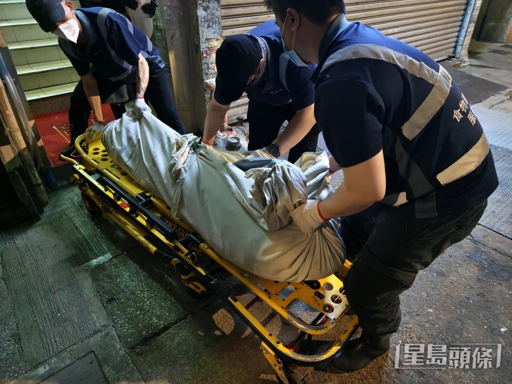 仵工將女死者的遺體搬落樓。