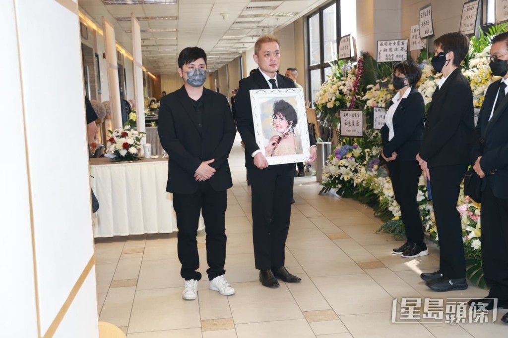 李泳漢捧着施明的遺照步出靈堂。 李泳漢捧着施明的遺照步出靈堂。