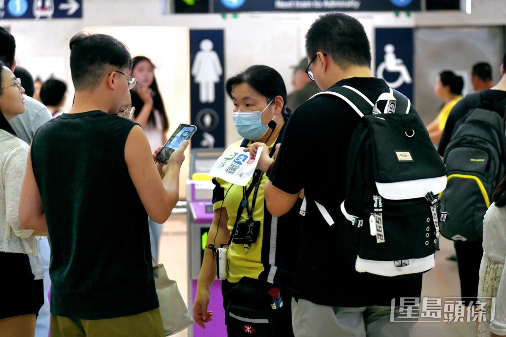 不少遊客使用二維碼入閘，港鐵職員在旁幫助，現場秩序良好。